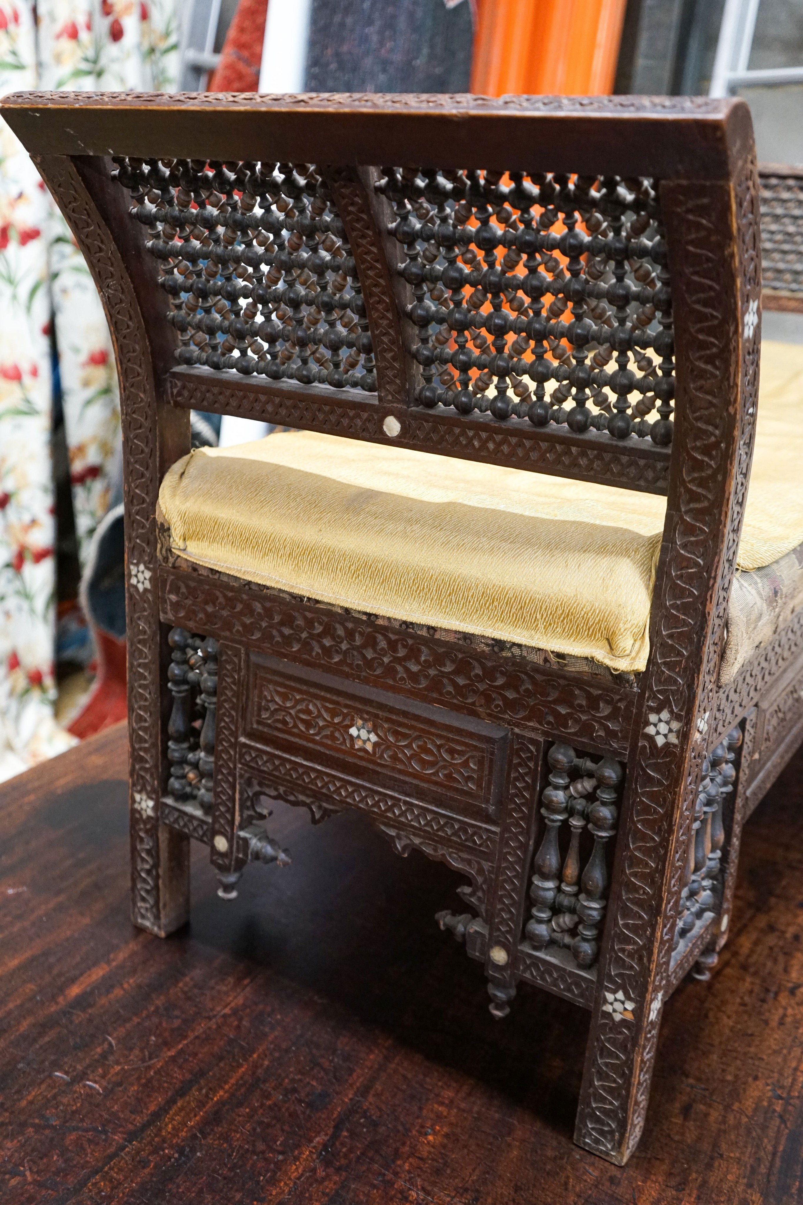 An early 20th century Moorish mother of pearl inlaid carved hardwood window seat, length 134cm, depth 44cm, height 64cm